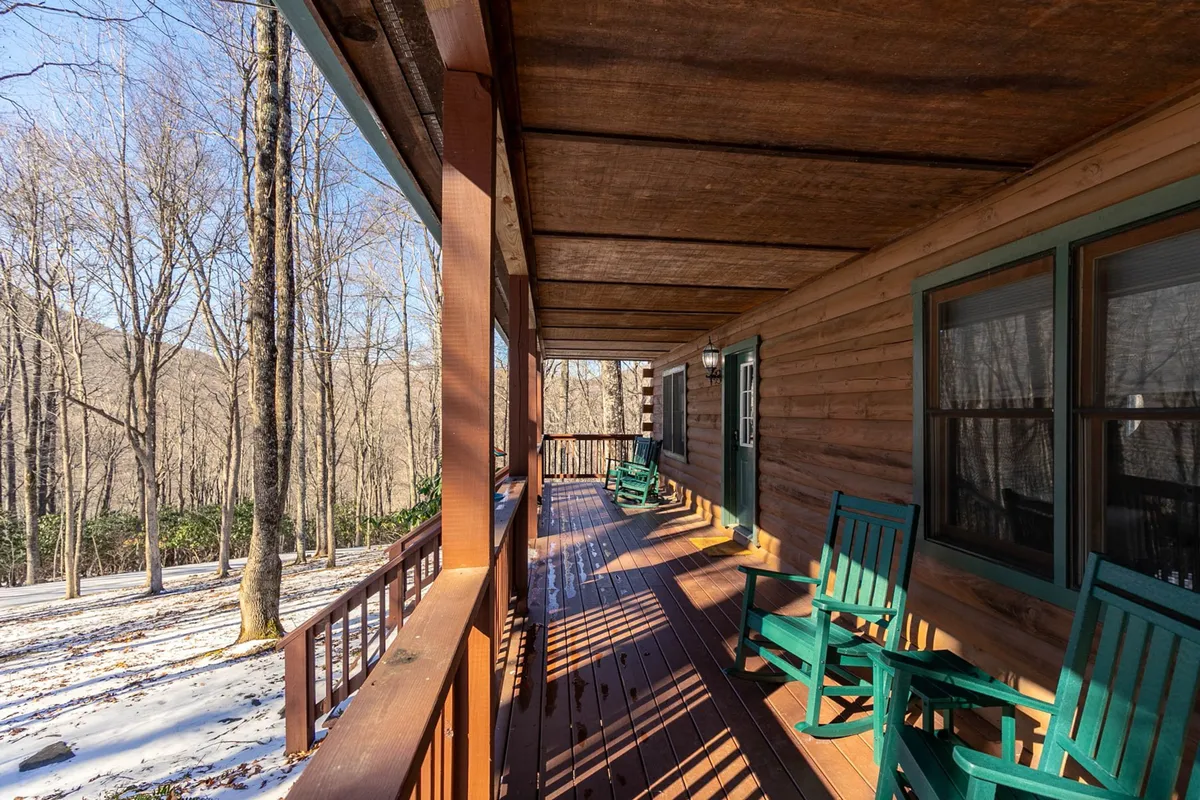 This image captures green rocking chairs on a wooden deck with a sweeping view of the surrounding landscape. The scene evokes relaxation, morning coffee, or winding down after work—all while connecting to nature.