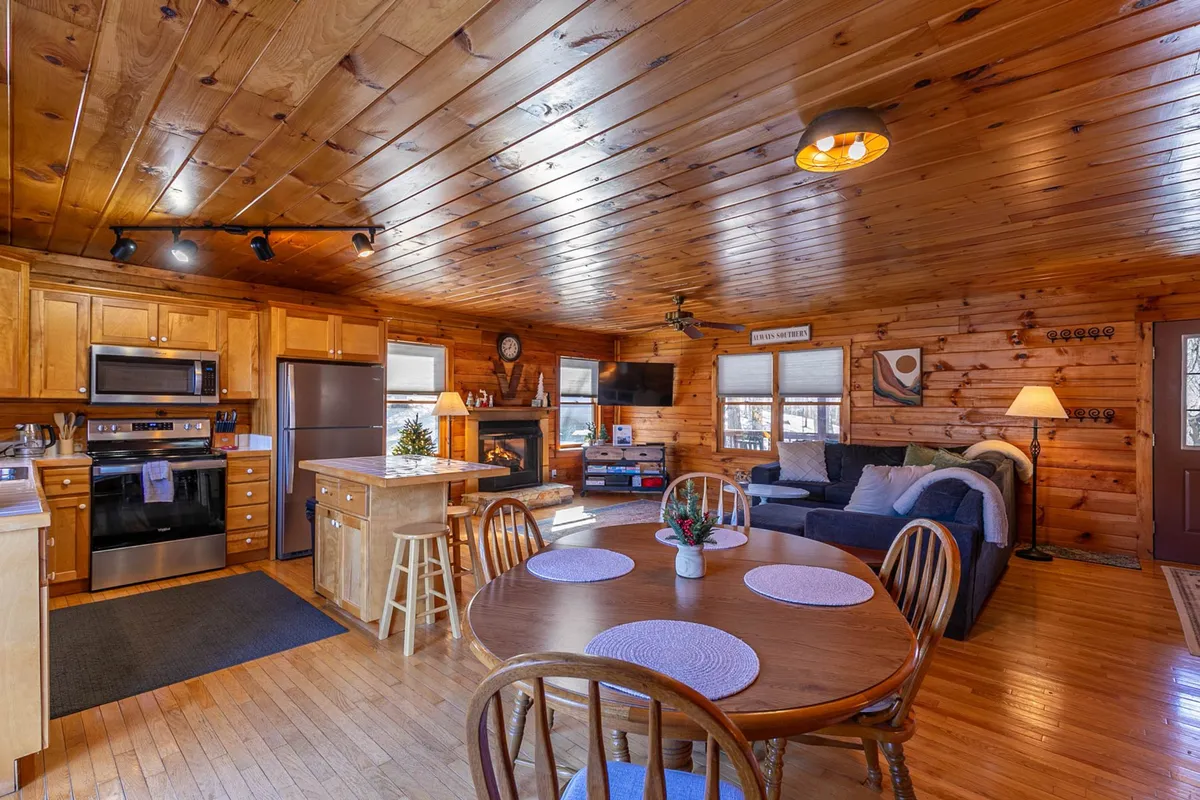A cozy, open-concept space that blends a dining table, kitchen island, fireplace, and a living area with a comfortable couch. The design fosters togetherness and easy flow between cooking, dining, and relaxing.
