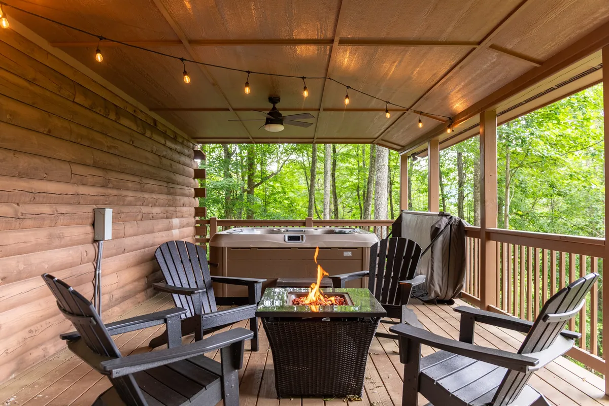 This exterior image highlights both a fire pit and a hot tub surrounded by lush greenery, with outdoor furniture arranged to enjoy the scenery. The inviting setup illustrates the perfect spot to unwind after a day of adventure, whether soaking in the hot tub or gathering around the fire under the open sky.